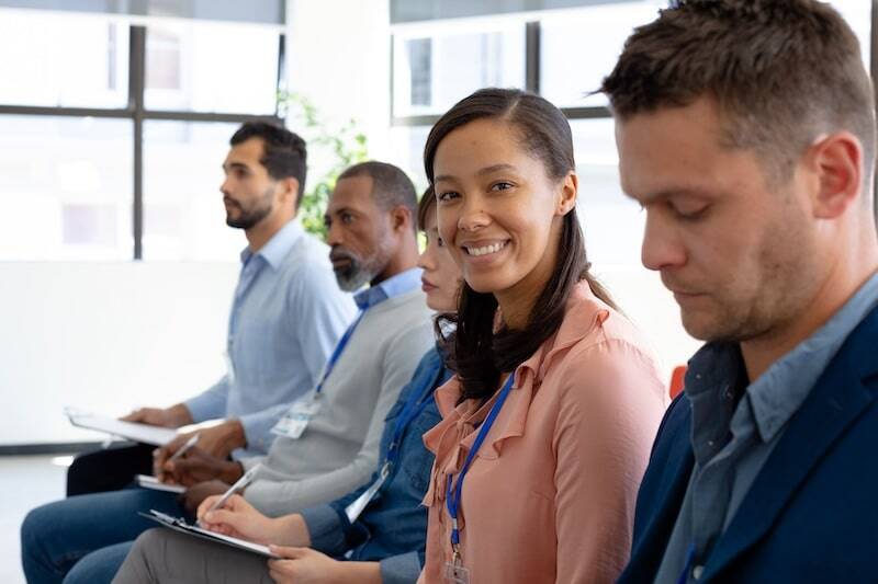 A woman smiles among a group of new employees receiving training